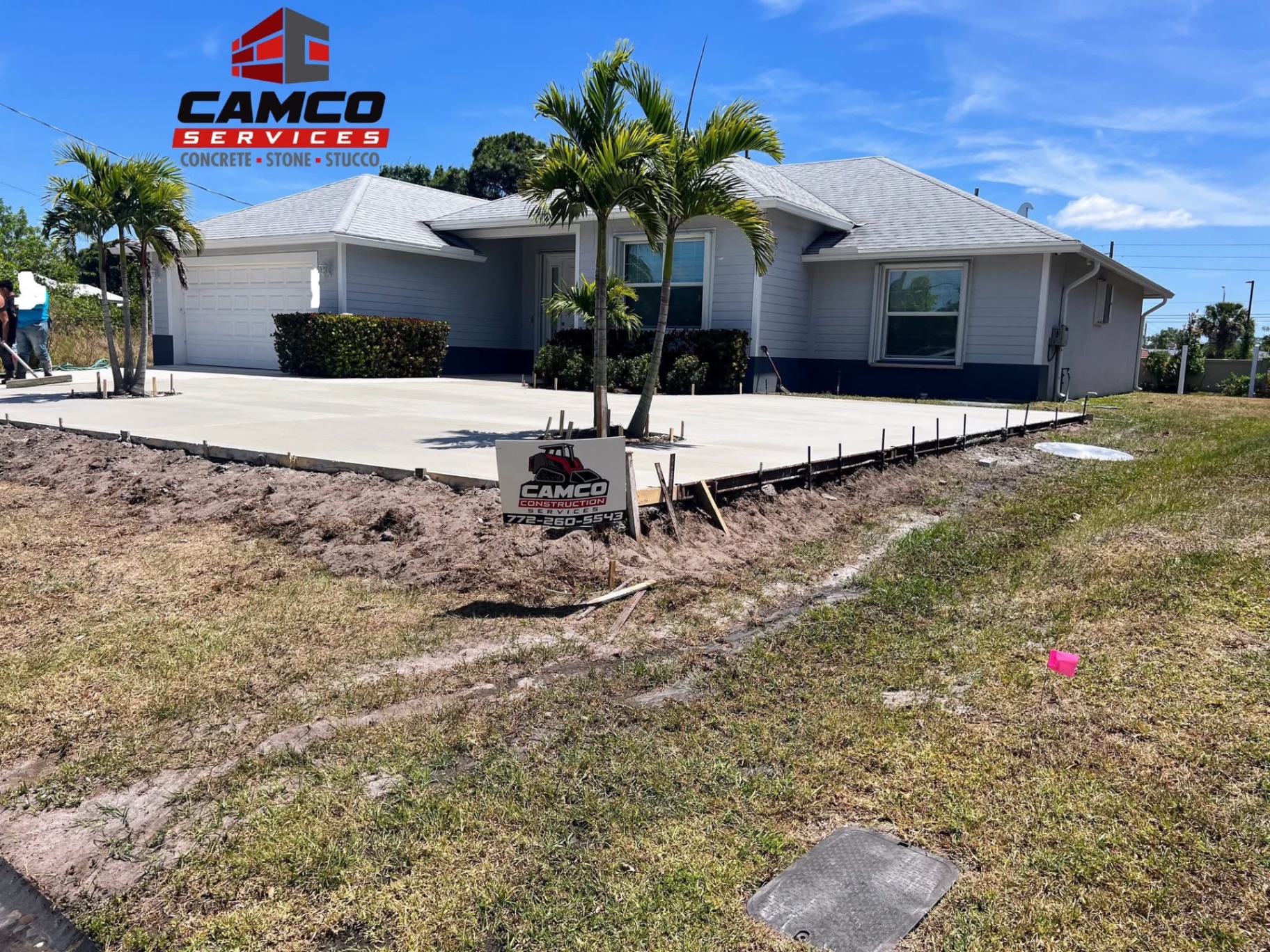 Wide poured concrete driveway around palm trees, still in forms