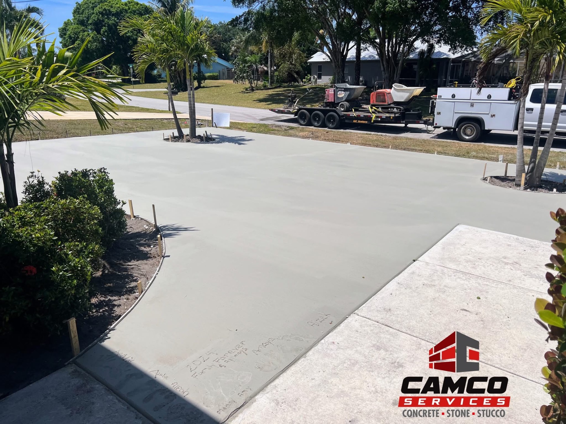 Freshly floated concrete parking pad with equipment trailer on the street